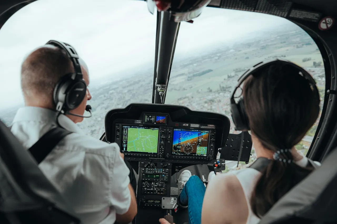 Pilot and passenger in the cockpit looking out over the landscape during a helicopter flight