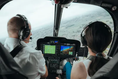 Pilot and passenger in the cockpit looking out over the landscape during a helicopter flight