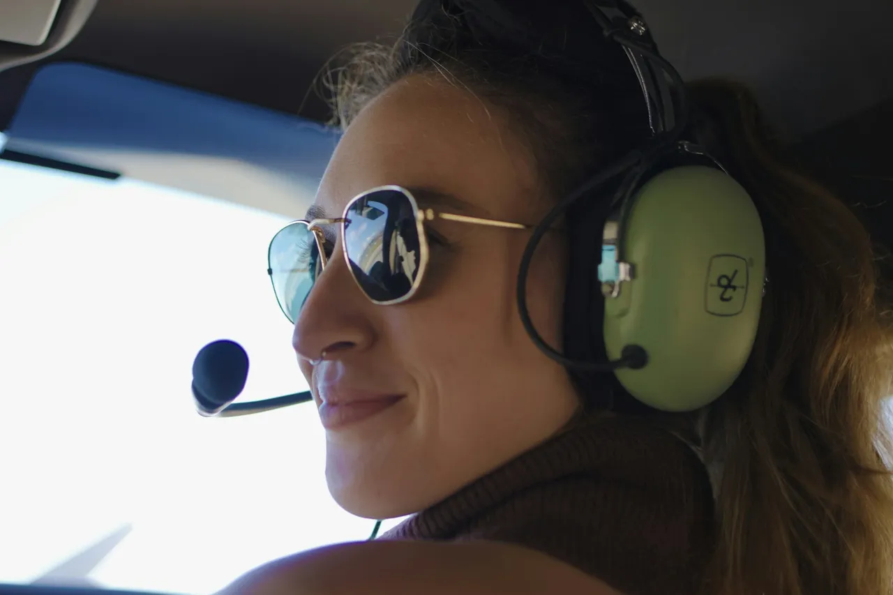 Smiling woman wearing a headset and sunglasses during a helicopter sightseeing flight