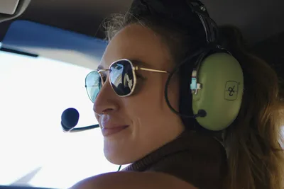 Smiling woman wearing a headset and sunglasses during a helicopter sightseeing flight