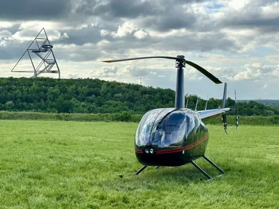 A red and black helicopter on a grassy field.