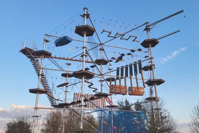 Multi-level high ropes course tower with platforms and obstacles against a blue sky