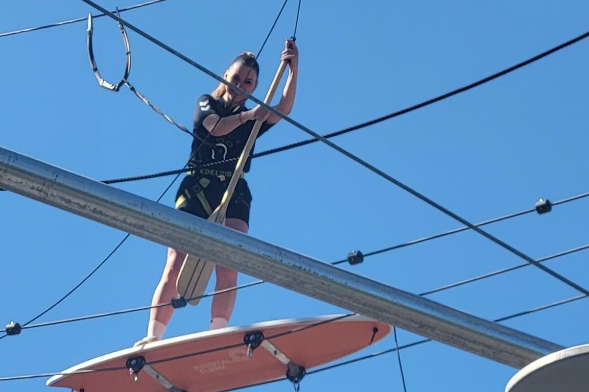Woman balancing on a board with a paddle in a high ropes course