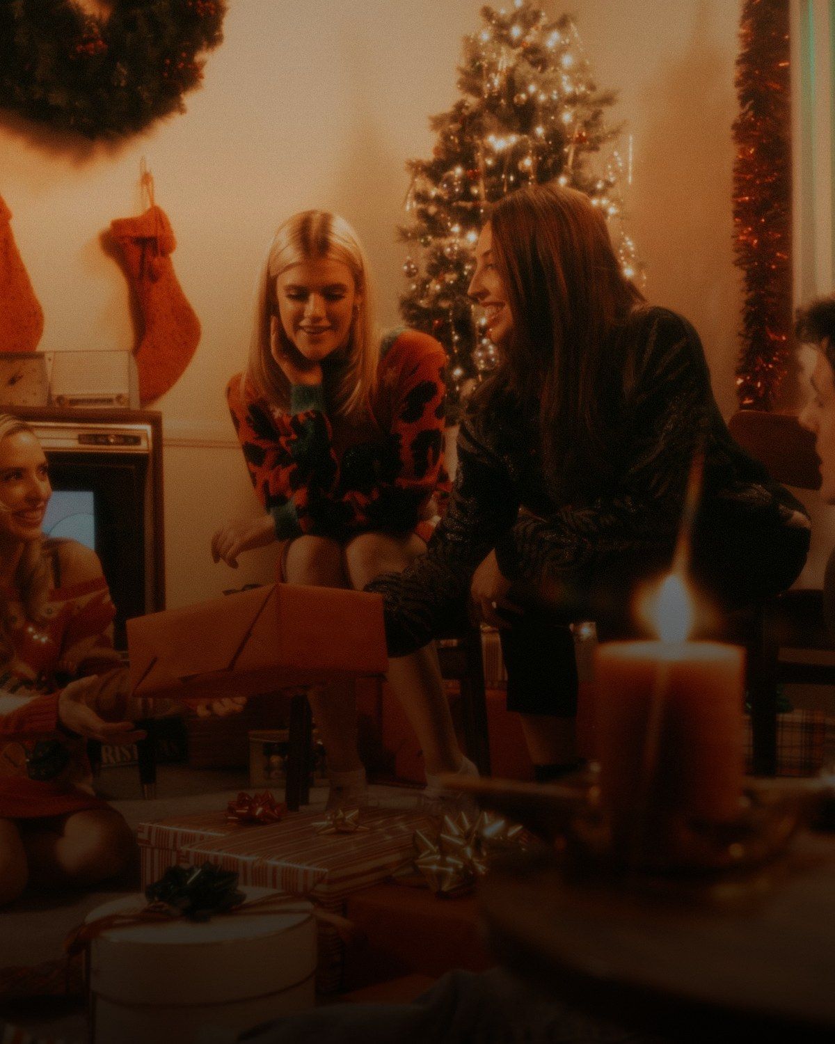 Friends exchanging gifts around a candlelit table on a festive evening