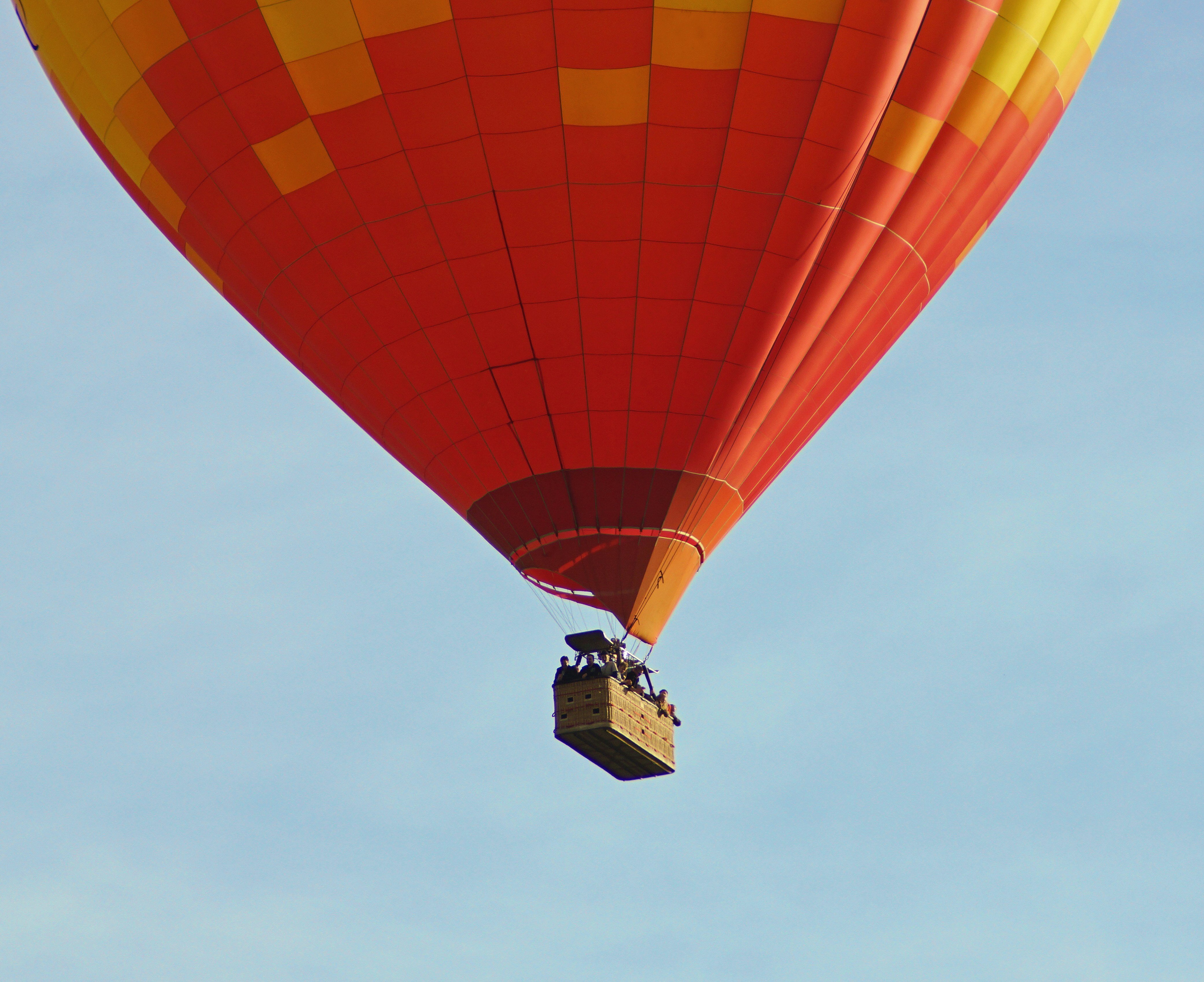 A large hot air balloon resting on a grassy field as ground crew prepare it for deflation.