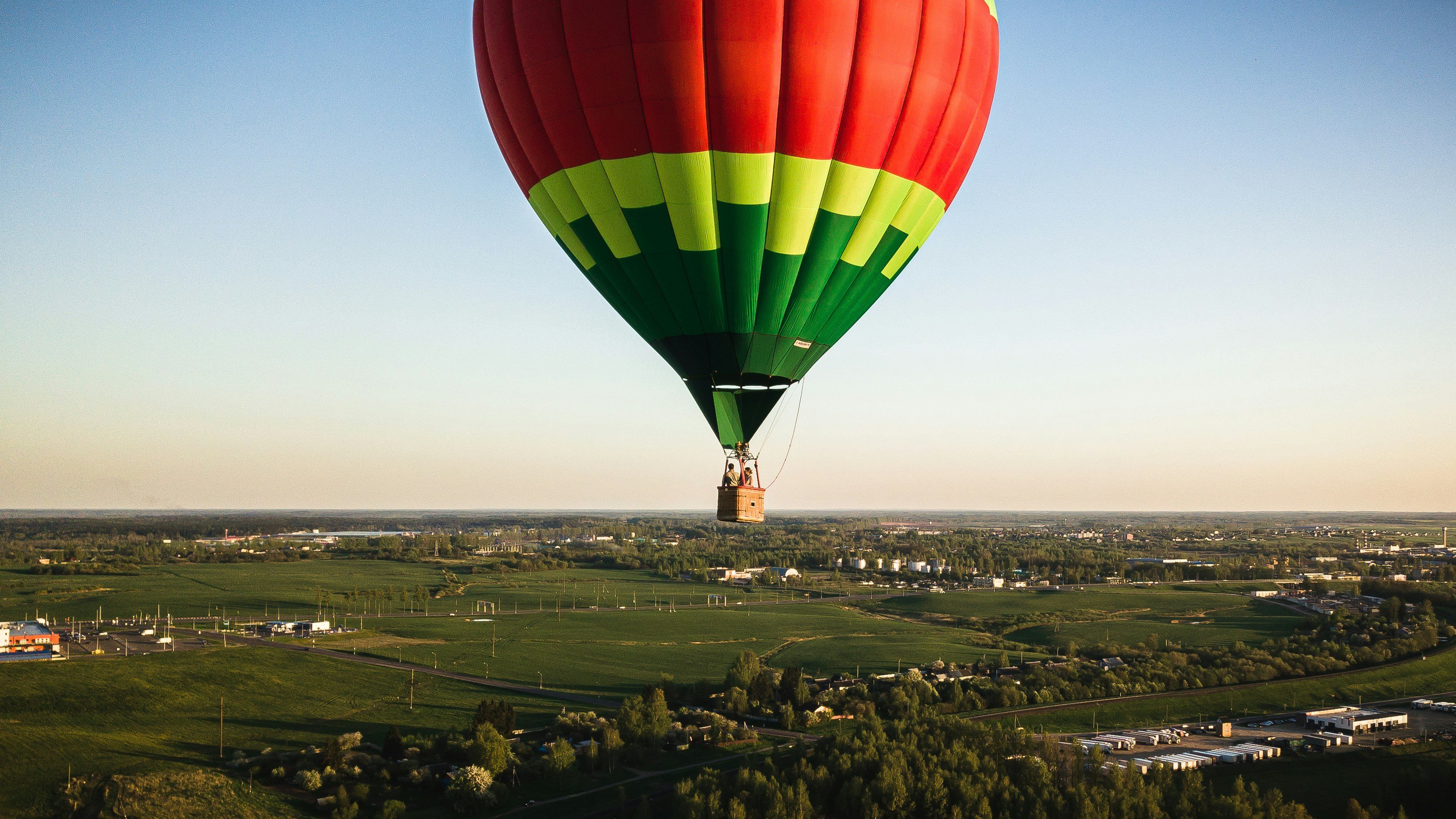 Colourful hot air balloon floating over the landscape at sunset