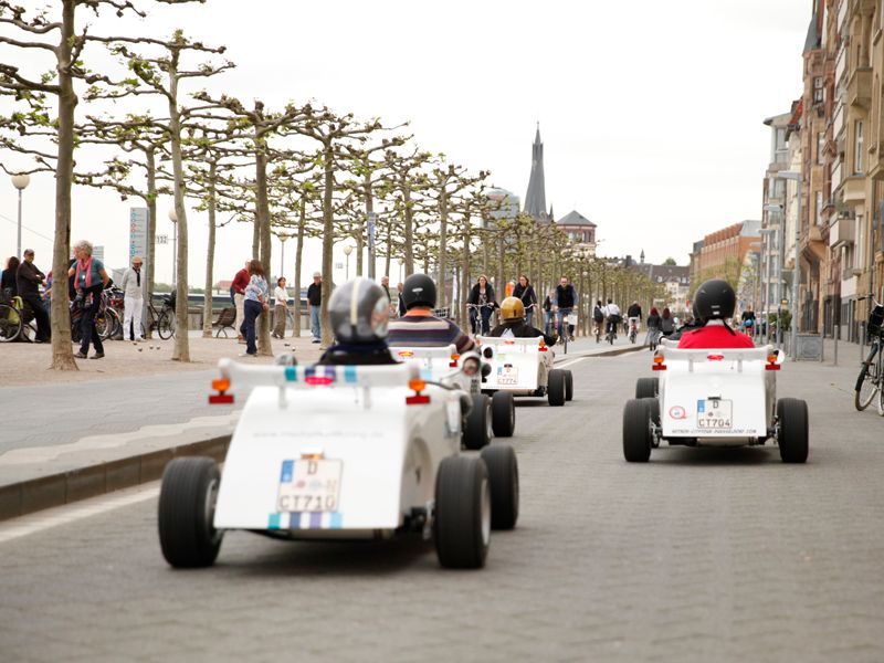 A group of mini hotrods driving through the city