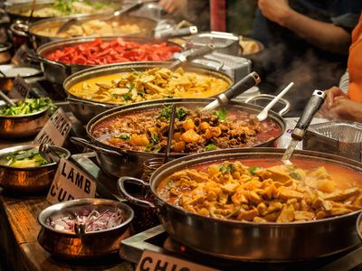 Large pans of Indian curries at a street food stall