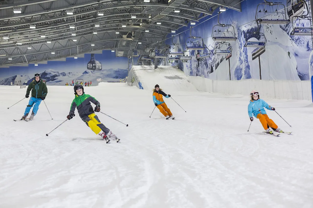 Group of skiers carving down a groomed indoor slope