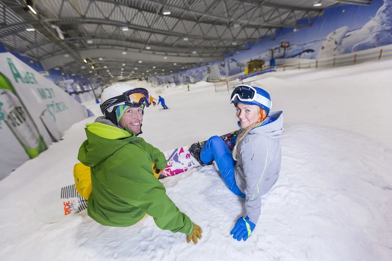 Two snowboarders sitting in the snow ready for their next run