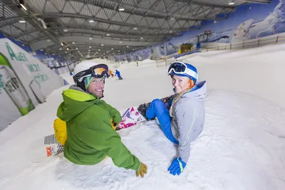 Two snowboarders sitting in the snow ready for their next run