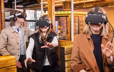 Three guests wearing VR headsets reaching out in amazement