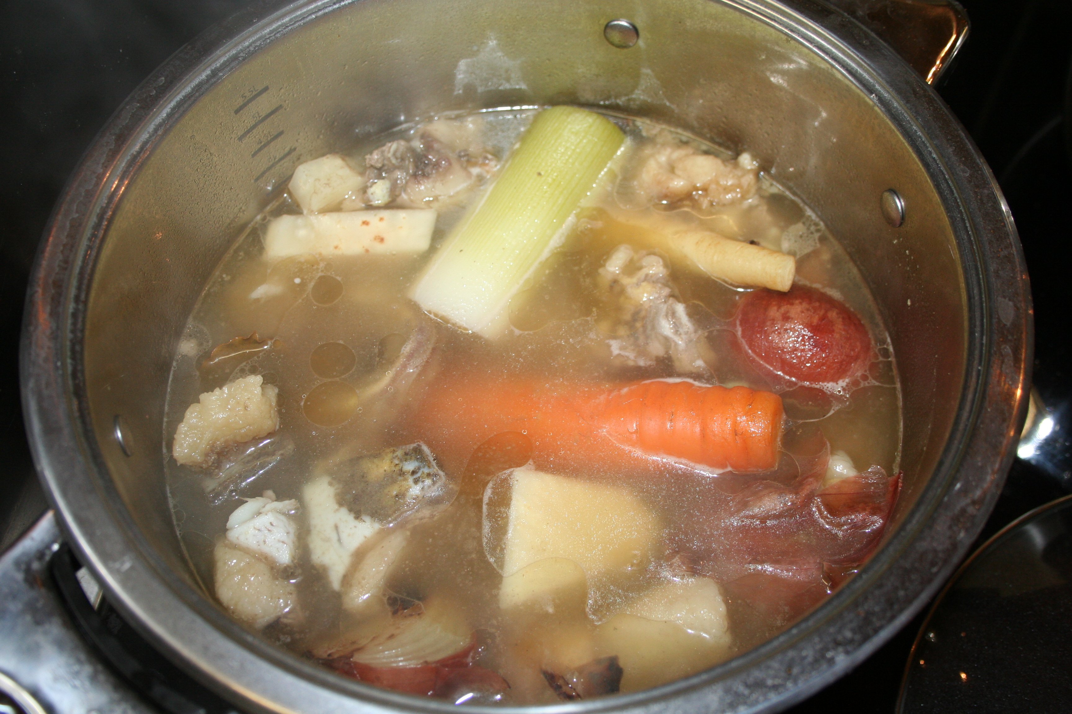 Homemade broth with vegetables simmering in a pot