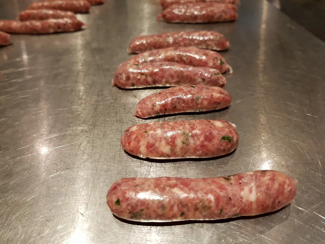 Raw bratwurst sausages lined up on a tray