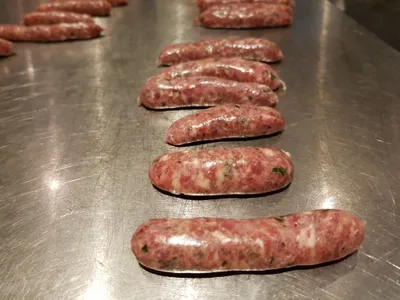 Raw bratwurst sausages lined up on a tray