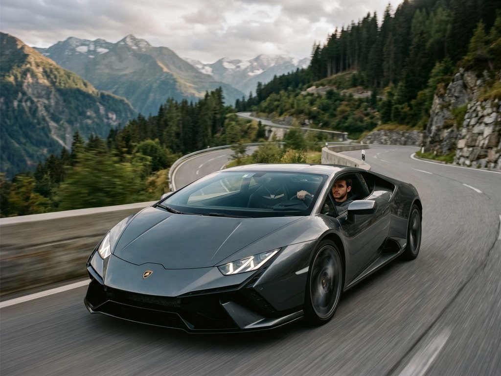 Dark Lamborghini supercar accelerating on a scenic road