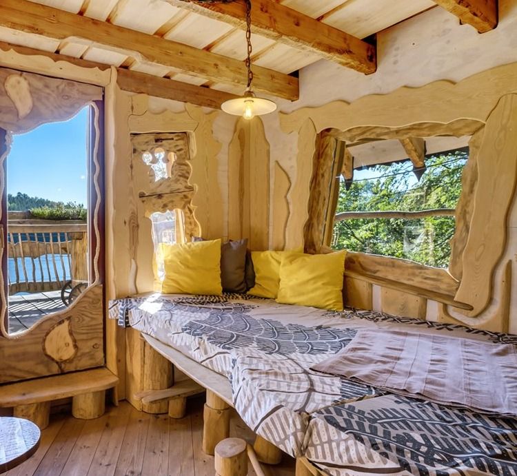 Cozy lounge with cushioned bench, yellow pillows and large windows overlooking the lake