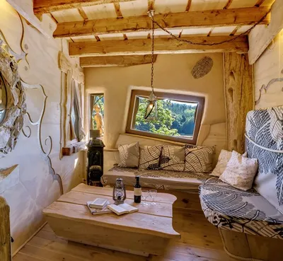 Fireplace room in a treehouse with sofa, cushions, wooden coffee table and lake view window
