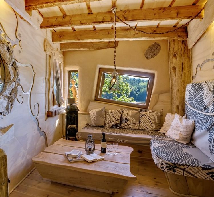 Fireplace room in a treehouse with sofa, cushions, wooden coffee table and lake view window