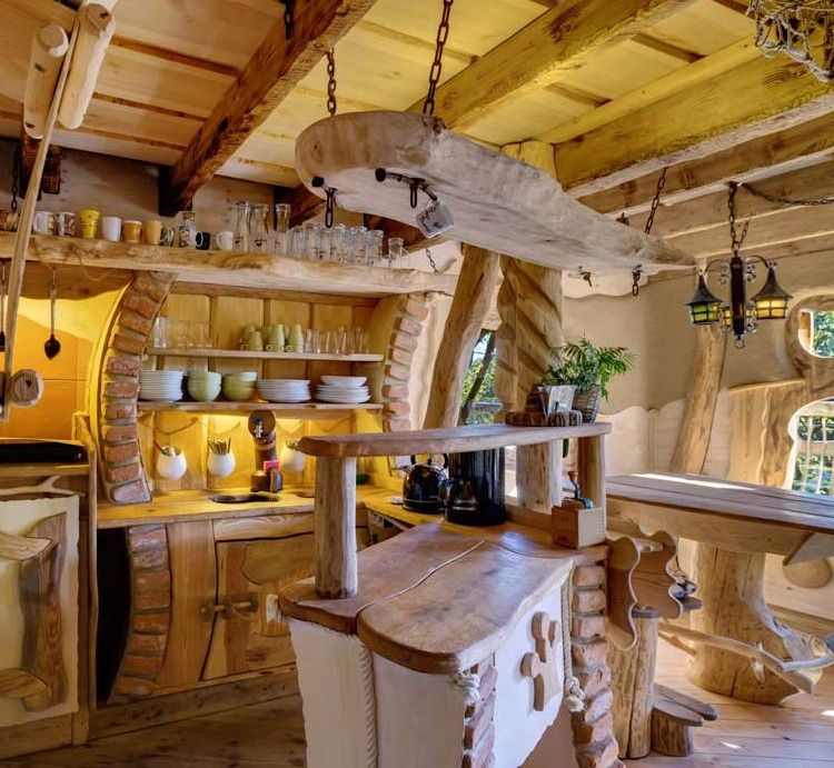 Handcrafted treehouse kitchen with carved wooden counter, open shelves and hanging lamp