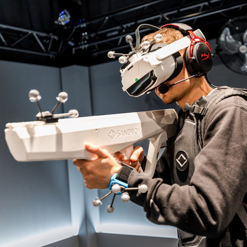 A boy holding with VR glasses holding a lasertag gun