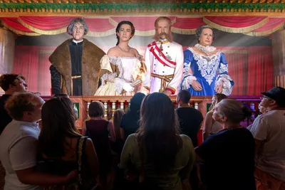 Visitors viewing a stage display of four figures representing Austrian imperial-era historical figures.