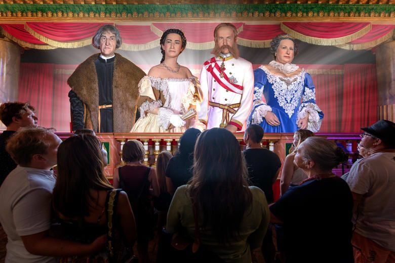 Visitors viewing a stage display of four figures representing Austrian imperial-era historical figures.