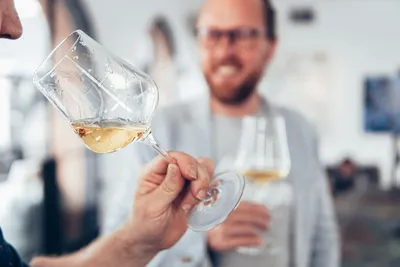 Smiling man tasting white wine with a friend