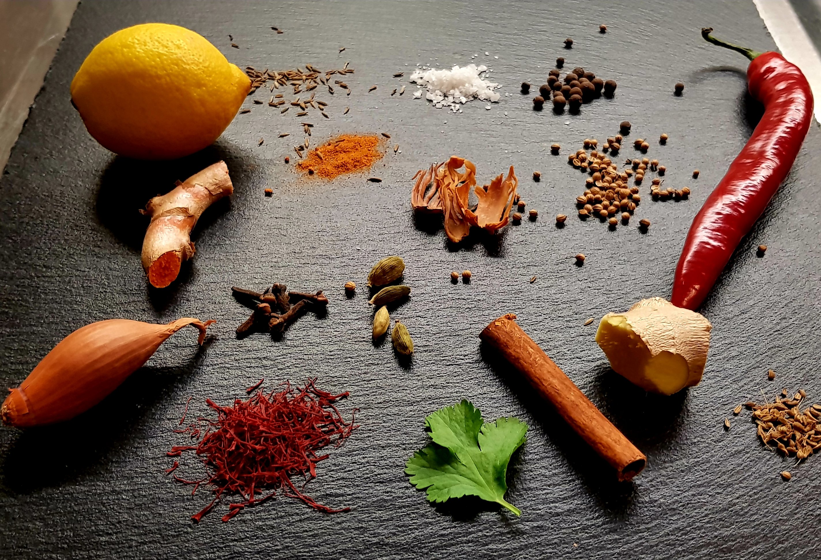 Spices, herbs and cooking ingredients arranged on a dark background
