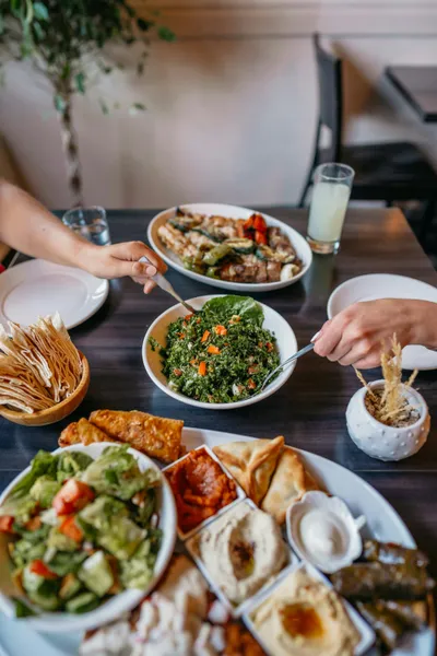 A fresh Mediterranean meal featuring grilled whole fish dressed with olive oil and herbs, accompanied by a colorful side salad of tomatoes, cucumbers, and olives.