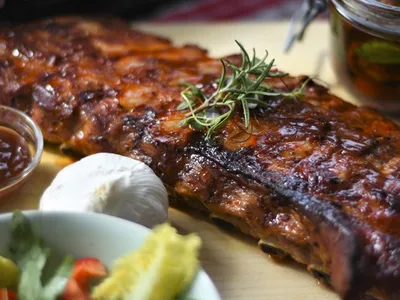 Glazed barbecue spare ribs garnished with rosemary, served with dip and fresh salad