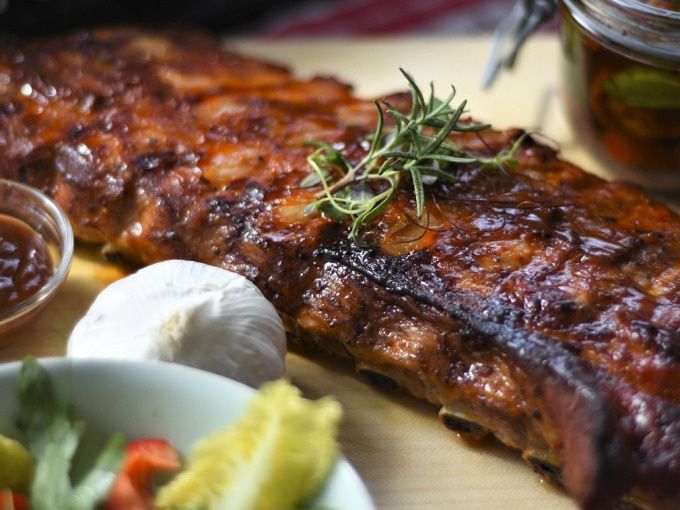 Glazed barbecue spare ribs garnished with rosemary, served with dip and fresh salad