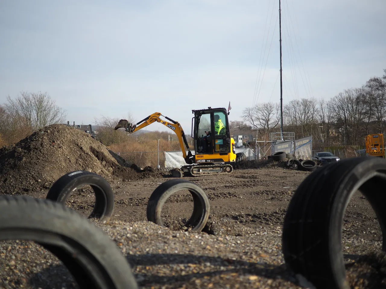 Person digging with a mini excavator next to a dirt pile