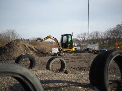 Person digging with a mini excavator next to a dirt pile