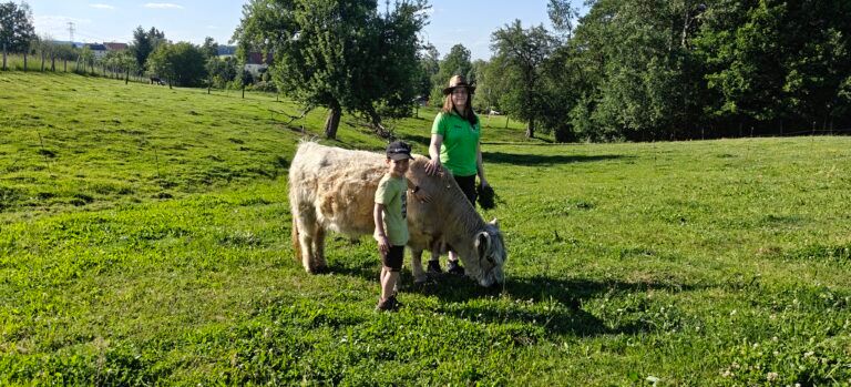 A boy and a woman next to a mini cow