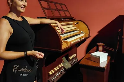 Smiling guide standing beside a historic organ in a music cabinet museum in Rüdesheim