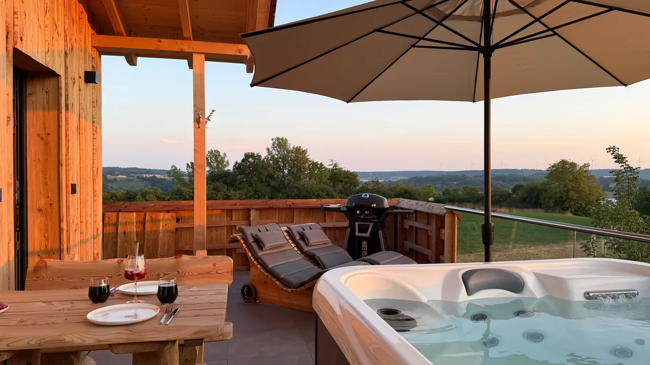Covered chalet terrace with hot tub, wooden dining table with wine glasses and sun loungers