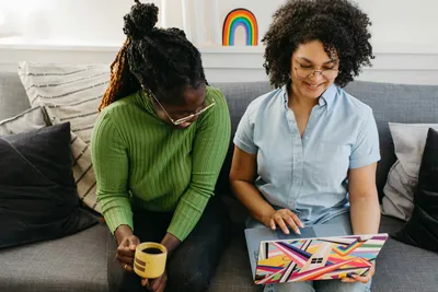 Two women sitting on a couch looking at a laptop