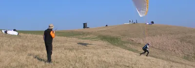 Paragliding students practising with their wings on a grassy training slope