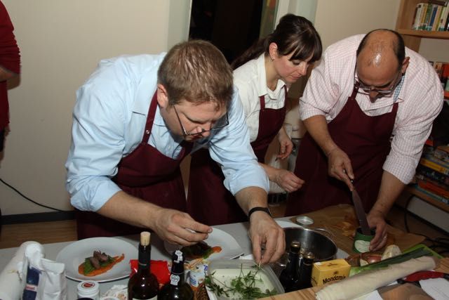 People in aprons carefully plating dishes during a cooking class
