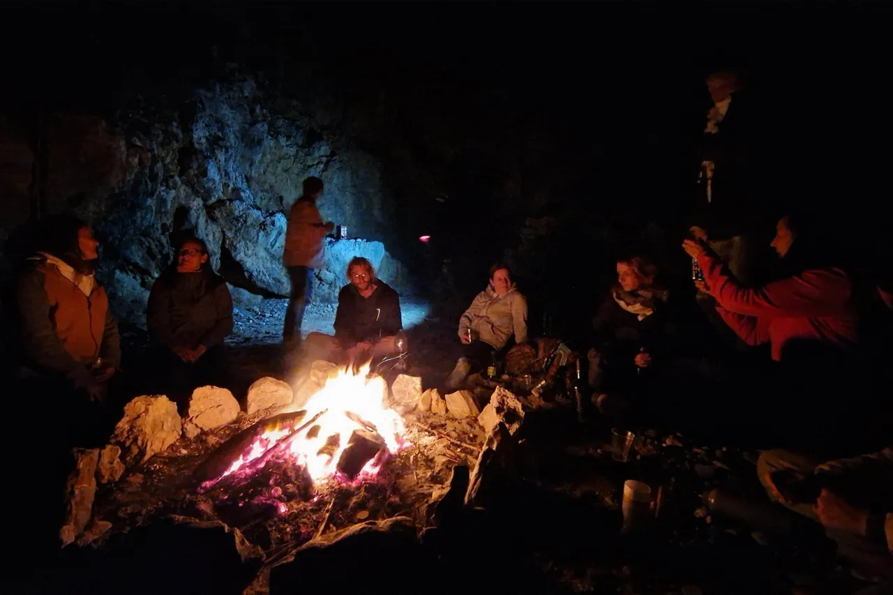 Group gathered around a crackling campfire at night during an ancestral fire ritual