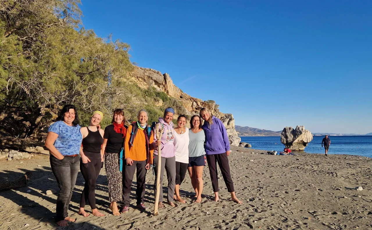 Smiling group of women standing barefoot together on a sunny beach