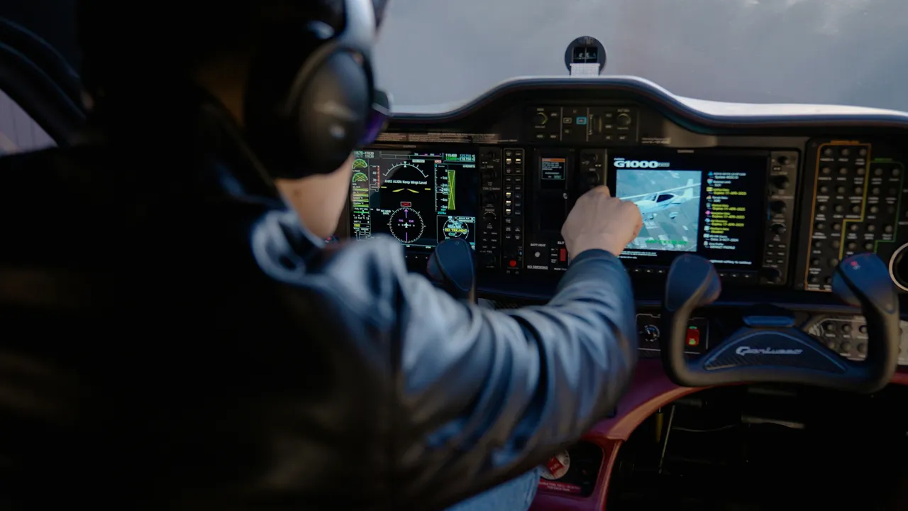 An over-the-shoulder view of a pilot wearing headphones while operating a Garmin G1000 flight simulator glass cockpit panel.