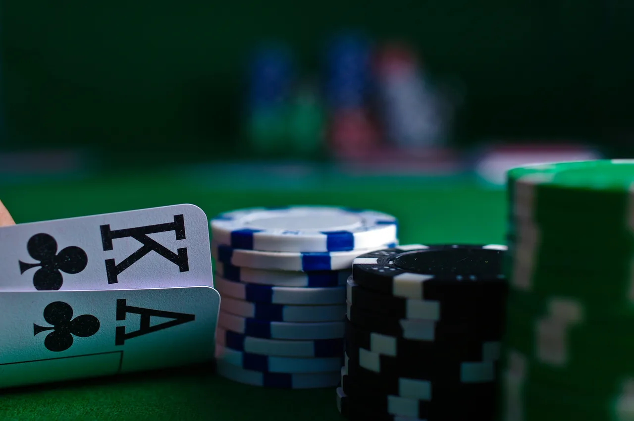 Pocket aces card hand beside stacked blue-white and black poker chips on green felt