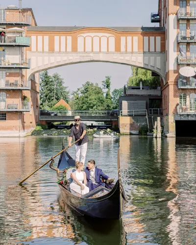 Couple on a gondola gliding beneath a historic arched brick bridge