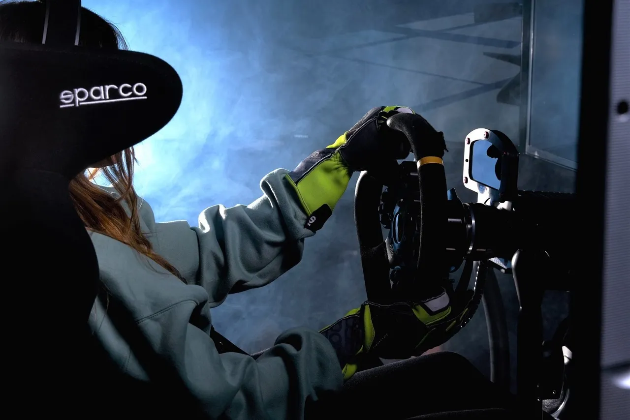 Driver in racing gloves gripping the steering wheel of a racing simulator in a dark cockpit