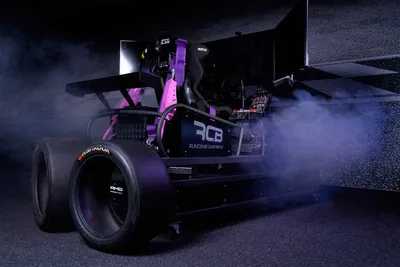 Full-motion racing simulator with bucket seat and slick tyre in a smoky, purple-lit arena