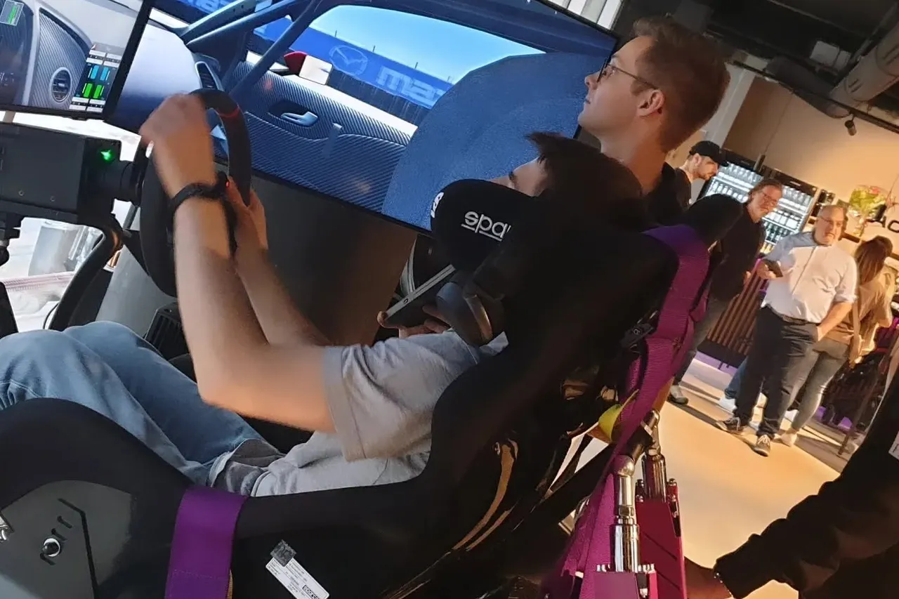 Two friends racing side by side in full-motion simulators in front of large screens