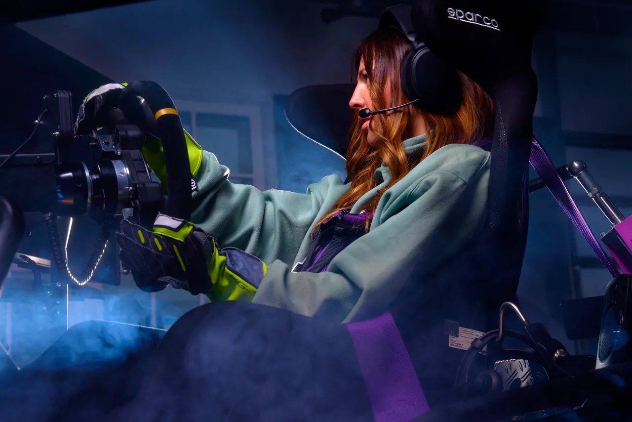 Woman with headset and racing gloves concentrating behind the wheel of a full-motion racing simulator