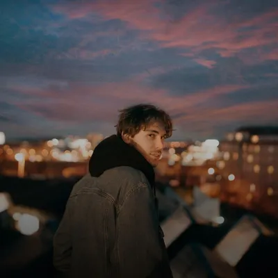 Gifts for your boyfriend: young man on a rooftop overlooking city lights at dusk